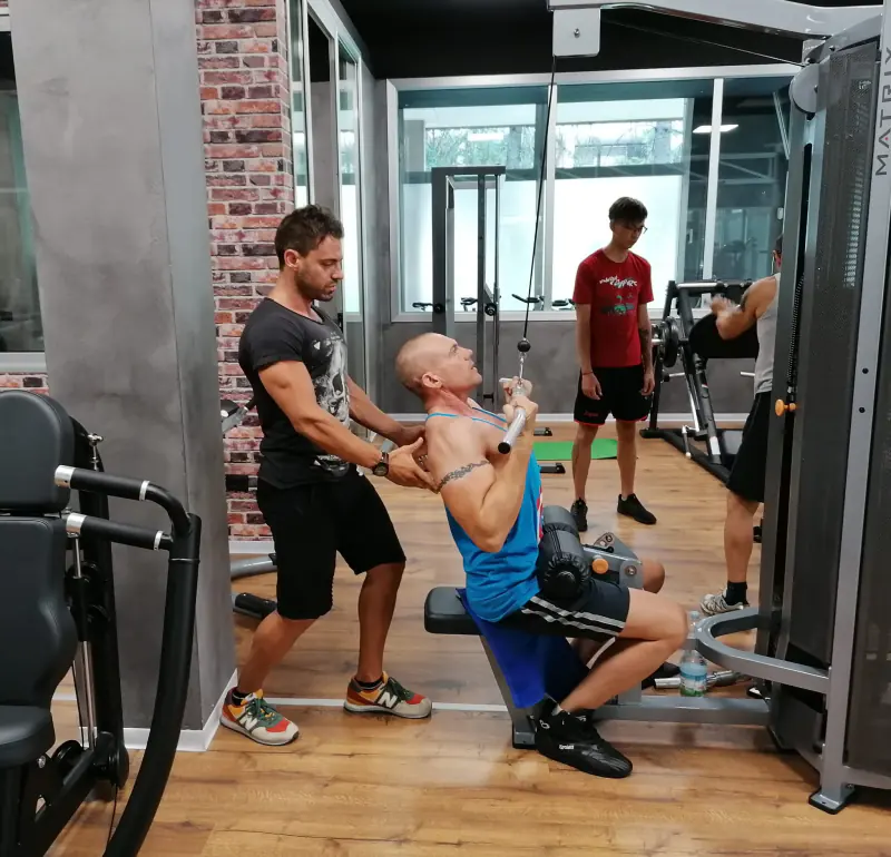 Cliente e personal trainer alle macchine in palestra